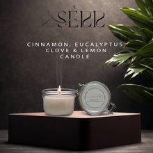 SerrBeauty Eucalyptus, Cinnamon, Clove & Lemon Beeswax Scented Candle in a glass jar with a lit wick, placed on a dark platform. Organic and handcrafted for a refreshing and warm home ambiance.