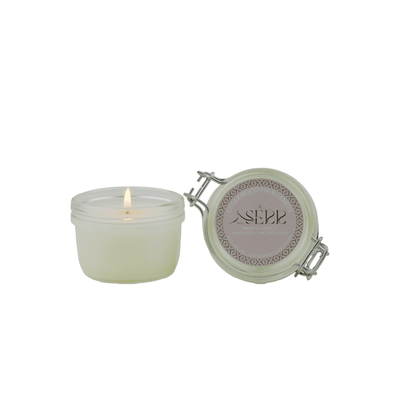 SerrBeauty Cedarwood, Fir & Lemon Beeswax Scented Candle 125 G in a glass jar with a lit wick. Organic beeswax candle with a refreshing woodsy citrus aroma.