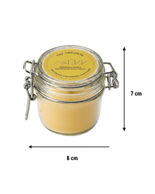 Unlit natural beeswax candle in a clear glass jar with a metal clasp, yellow label with black text, handmade, long burning, and wooden wick