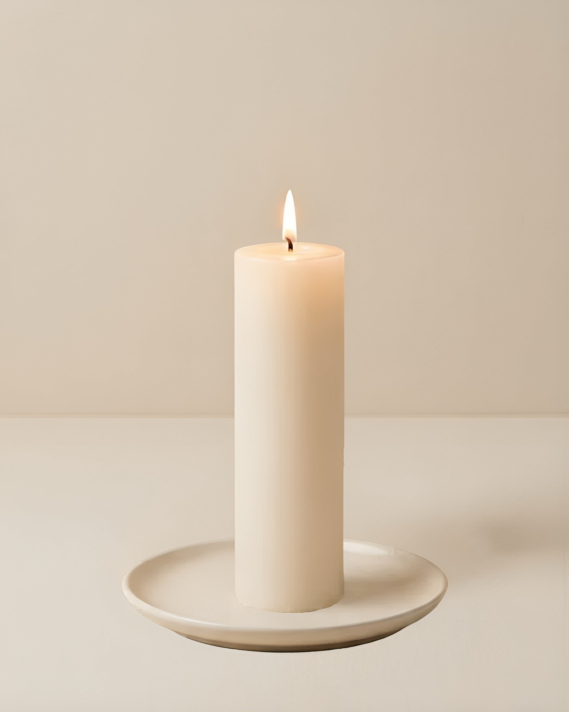 Everyday unscented rapeseed wax pillar candle 44g burning on a ceramic plate