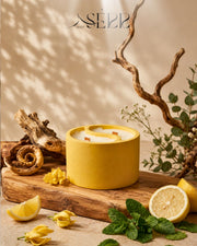 Yellow concrete candle with wood wicks, surrounded by citrus fruits, cozy home ambiance