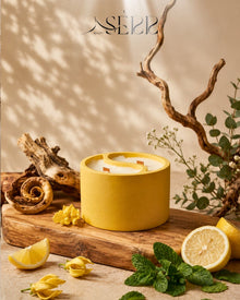 Yellow concrete candle with wood wicks, surrounded by citrus fruits, cozy home ambiance